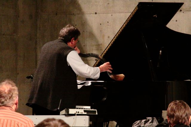 Curran blowing the ancient shofar (ram's horn) over the undamped piano strings.